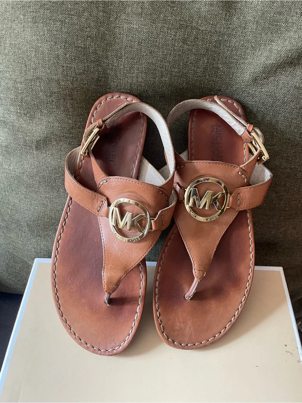 Michael Kors tan leather thong sandals feature a polished gold-tone MK log